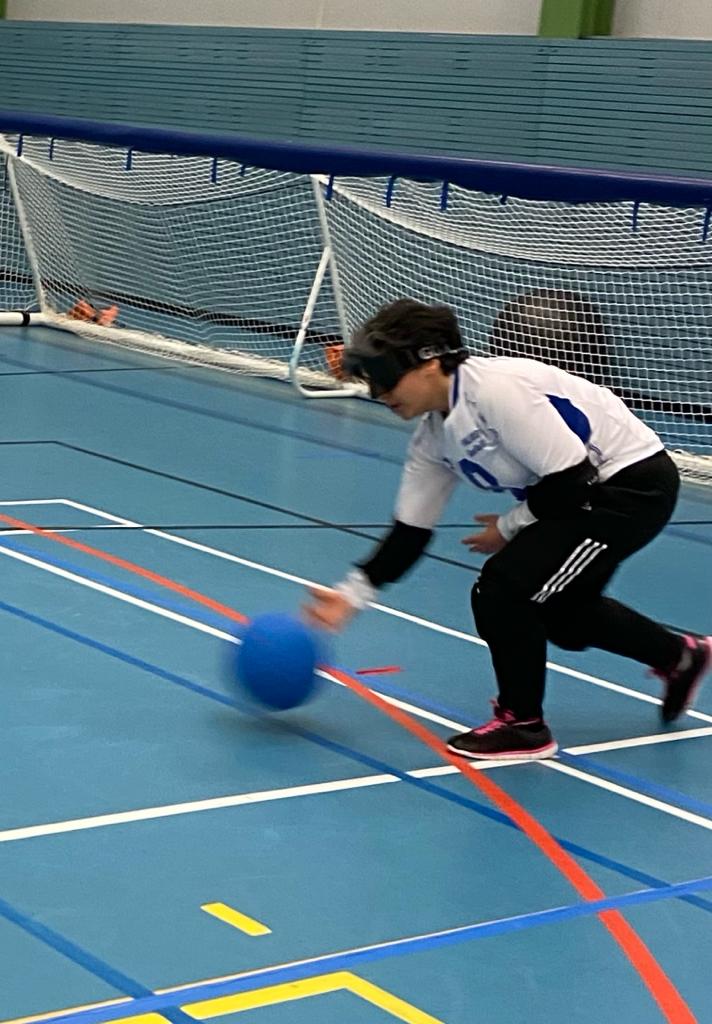 Kuva Azrasta pelaamassa. Azra pelaa seiska laidassa ja on juuri heittänyt palloa. Pallo näkyy kuvassa vasemmalla. Azralla on valkoinen Suomi-paita ja mustat pelihousut.